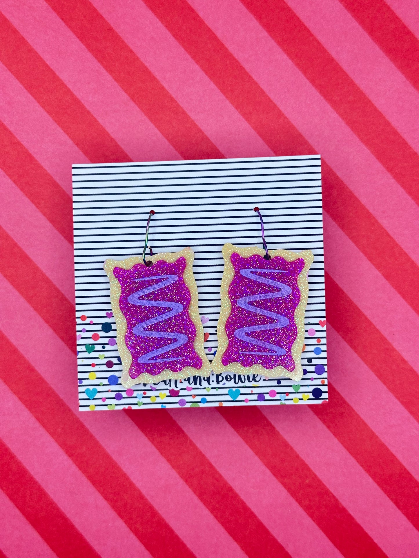 Breakfast pastry earrings displayed on a pink and red stripe background