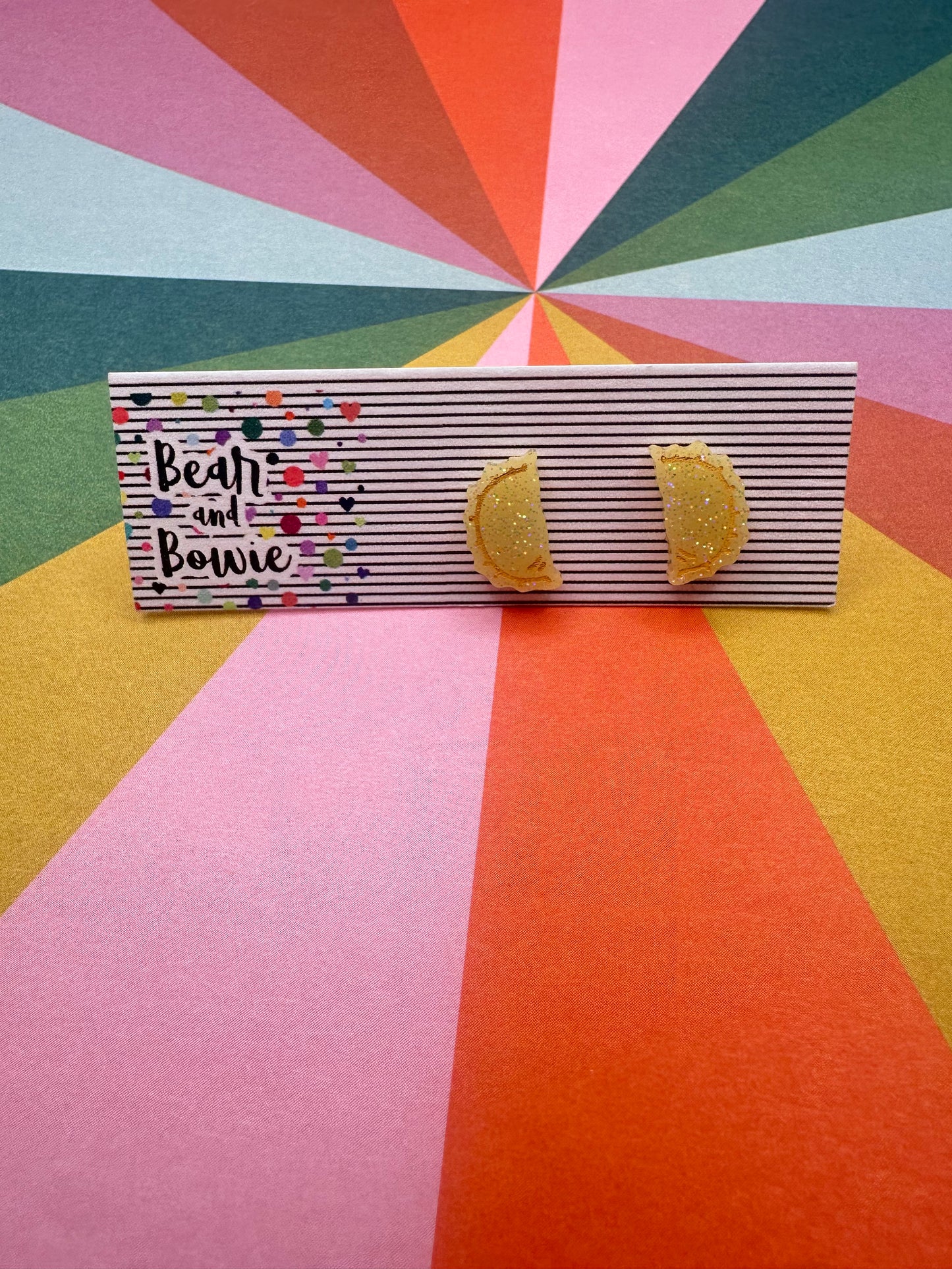Tan pierogi earrings on a geometric patterned background