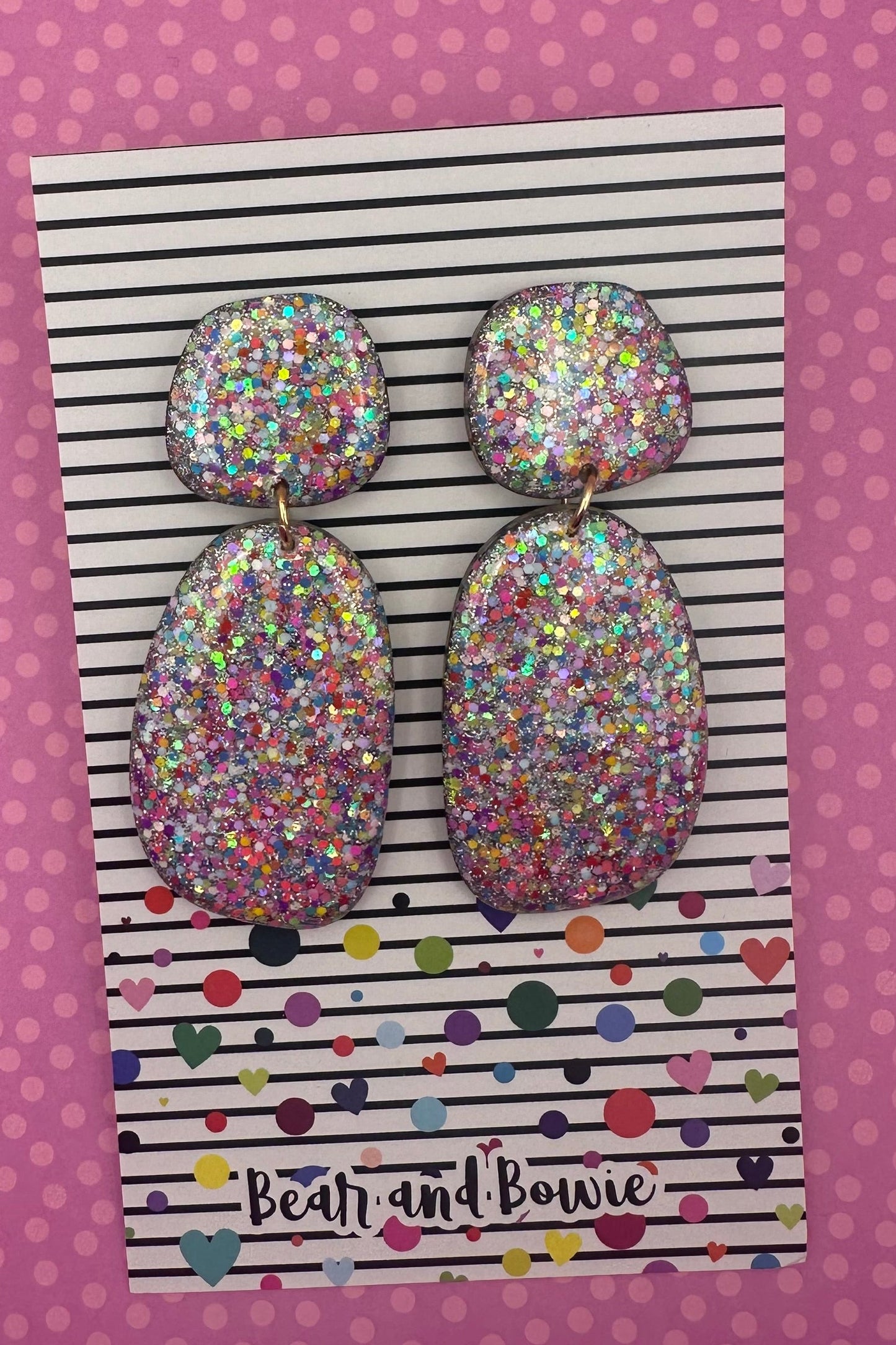 Set of glittery earrings on a striped card with 'Bear and Bowie' branding against a pink polka dot background.