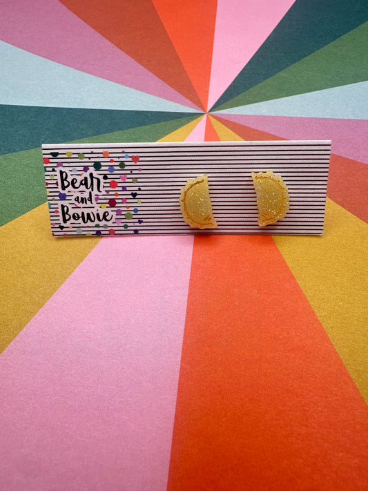 Tan pierogi earrings on a geometric patterned background