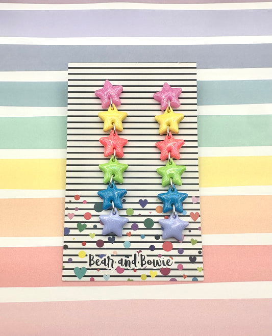 Colorful star-shaped earrings on a striped background with 'Bear and Bowie' branding.