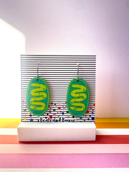 Pair of green and teal mitochondria earrings on a stand with colorful background